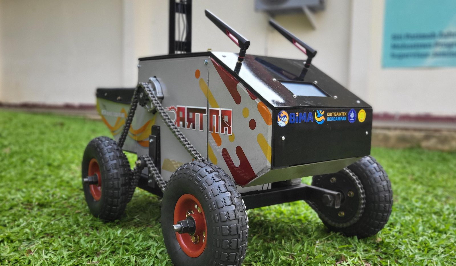 The assembled ANTRAC 1.0 UGV: boxy four-wheel chassis with a mast-mounted sensor head, on grass.