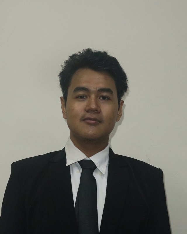 Muhammad Faiz Assariy in a suit against a plain wall.