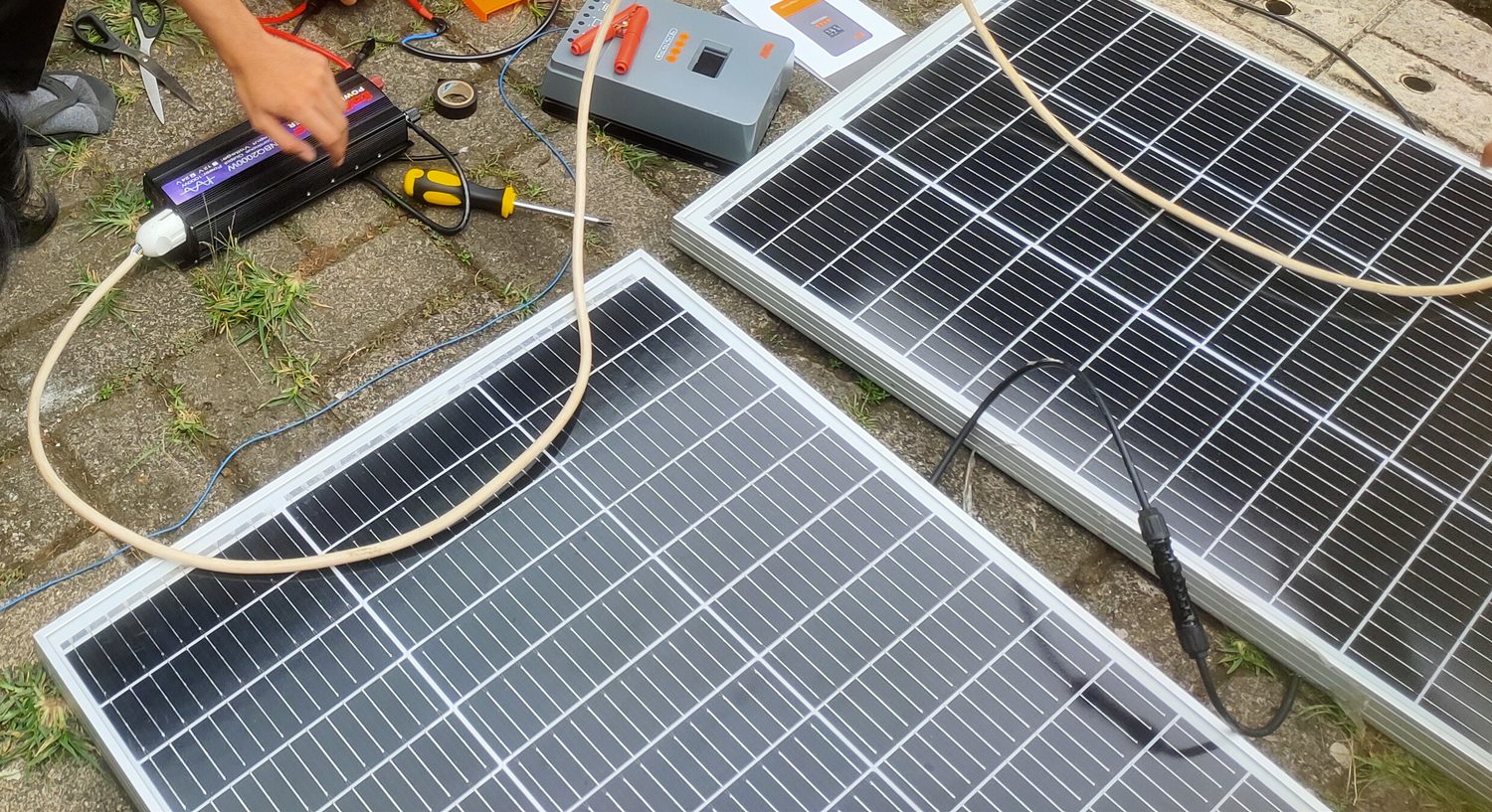 Build documentation: charge controller, coiled cable, tools and two solar panels laid flat during assembly.
