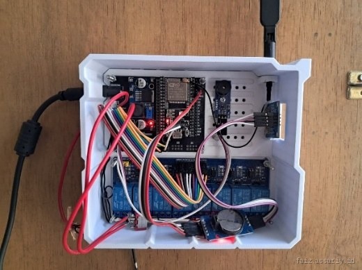 Open control enclosure showing an ESP32 board, a multi-channel relay board, an RTC module with coin cell, and jumper wiring.