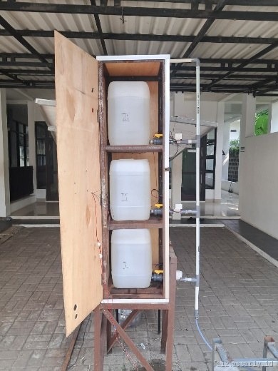 The built station: welded steel frame with three white 20 litre tanks on individual ball valves, PVC manifold and a pump at the base.